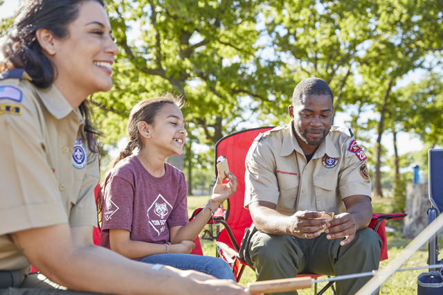 Adult leaders sitting around campfire with young Scout.